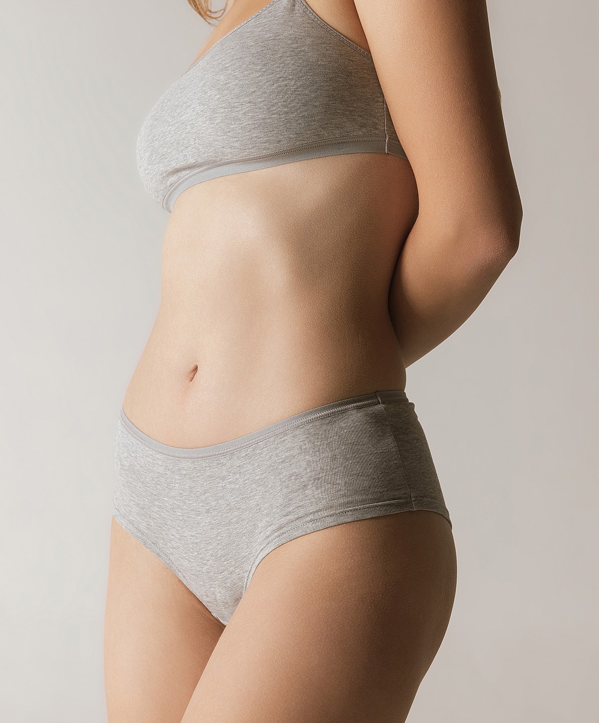 Woman in gray underwear against a neutral background.