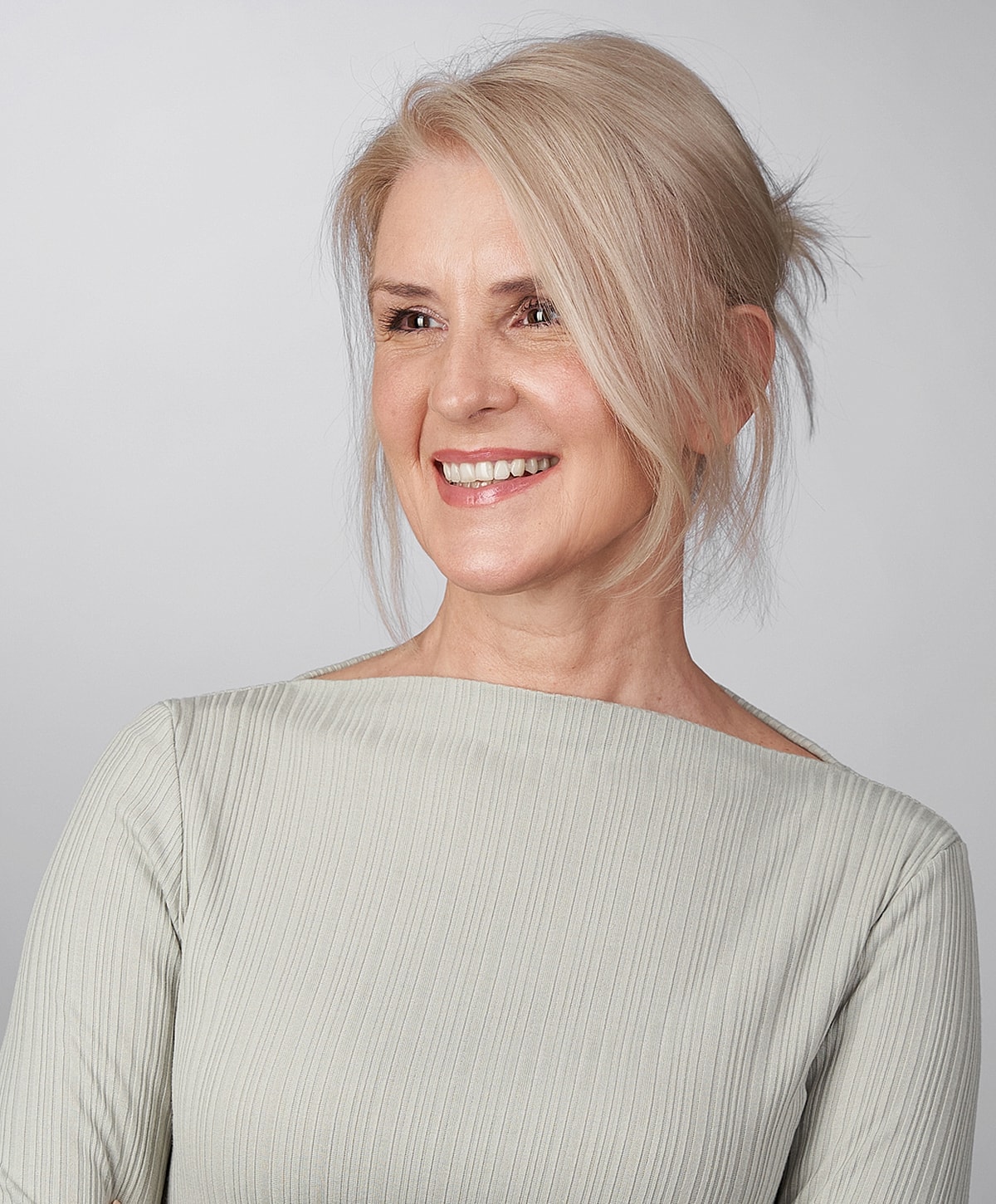 Smiling woman with light blonde hair, neutral background.