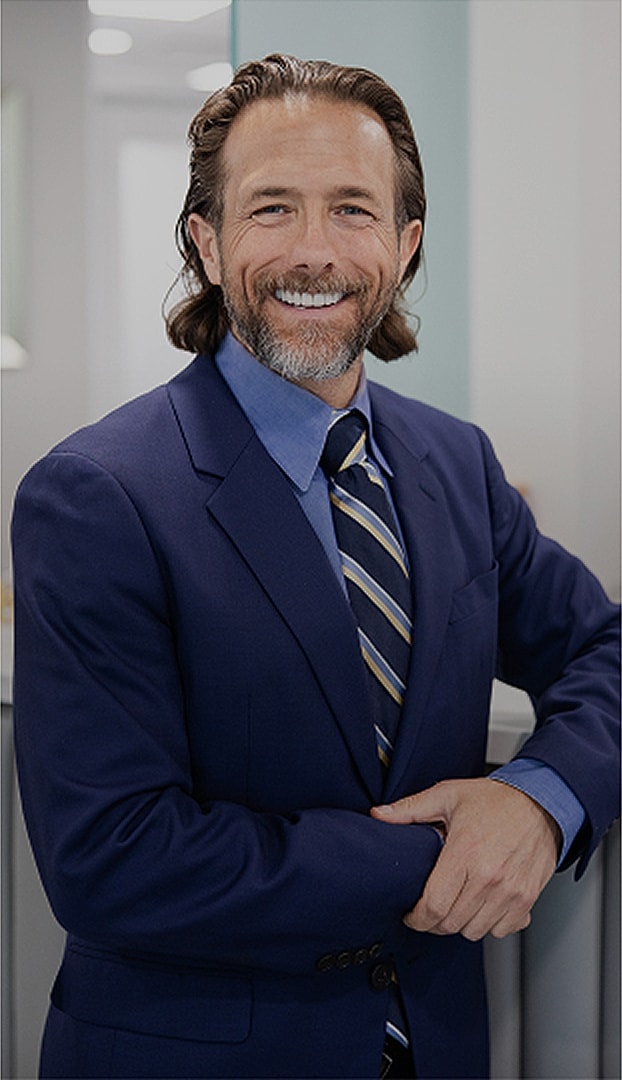 Smiling man in a suit, standing confidently.